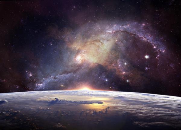 An image of the Earth with a galaxy above it.