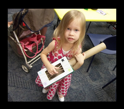 A child playing a home-made tissue box guitar