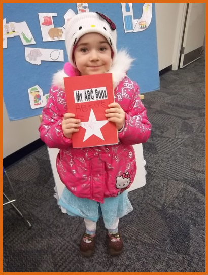 A child holding an alphabet book - she learned her letters while making it!